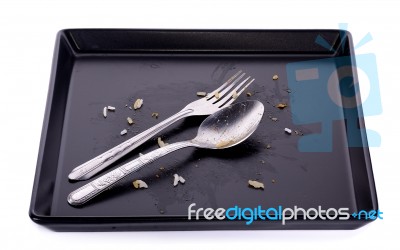 Empty And Dirty Black Plate With Spoon Isolated On White Stock Photo