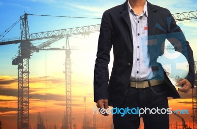 Engineer Man Working With White Safety Helmet Against Crane And Stock Photo