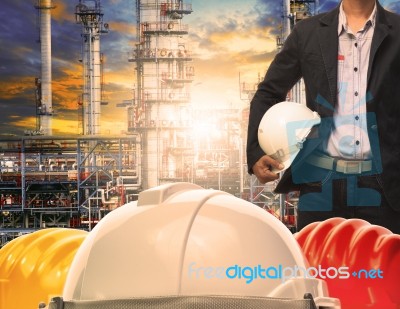 Engineering Man With White Safety Helmet Standing In Front Of Oil Refinery Building Structure In Heavy Petrochemical Industry Stock Photo