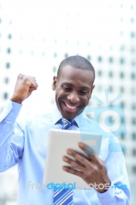 Executive Celebrates His Success Holding A Tablet Stock Photo