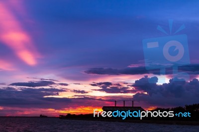 Factory Beside The Sea With Colorful Sunset Stock Photo