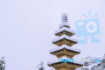 Falling Snow At Stone Statue In A Winter With Snow Covered Trees… Stock Photo