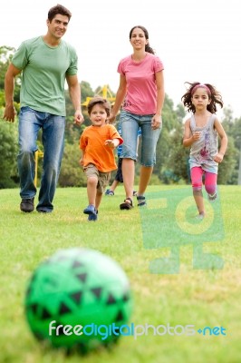 Family Playing Football In The Park Stock Photo