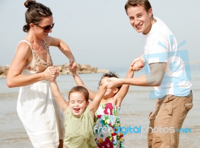 Family Playing On The Beach Stock Photo