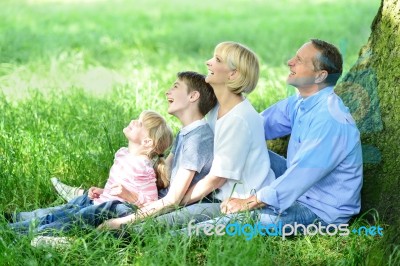 Family Sitting In Shade Under The Tree Stock Photo