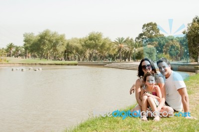 Family Sitting Near The Lake Stock Photo