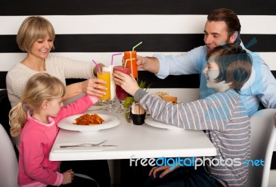 Family Toasting Smoothies In Restaurant Stock Photo