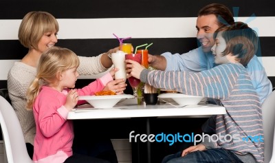 Family Toasting Smoothies In Restaurant Stock Photo