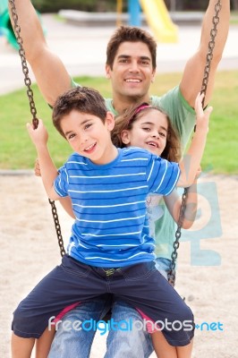 Father And Children Enjoying Swing Ride Stock Photo