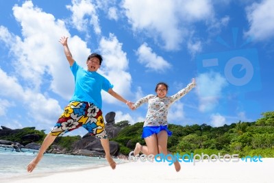 Father And Daughter Jumping On Beach At Thailand Stock Photo