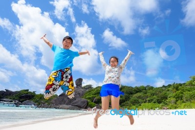 Father And Daughter Jumping On Beach At Thailand Stock Photo