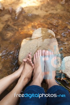 Feet Of Couple Sitting On The Stone Near River Stock Photo