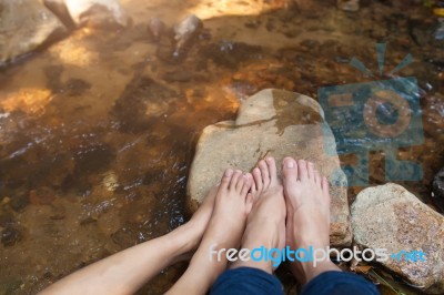 Feet Of Couple Sitting On The Stone Near River Stock Photo