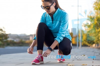 Female Athlete Tying Laces For Jogging Stock Photo