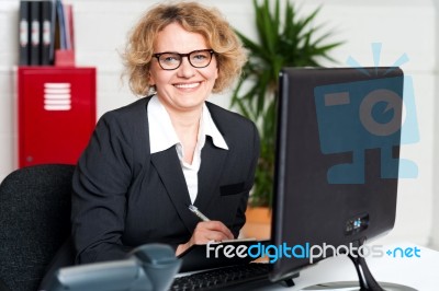 Female Executive Writing Notes On Clipboard Stock Photo