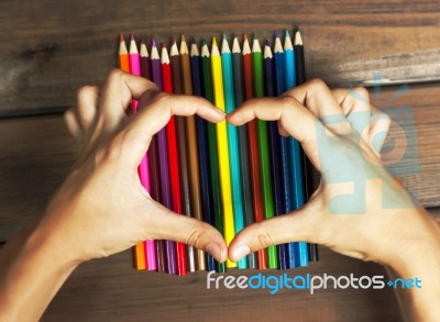 Female Hands In The Shape Of A Heart On Colored Pencils On A Bac… Stock Photo