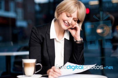 Female Reviewing Business Report In Cafe Stock Photo