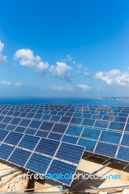 Field Of Solar Collectors Near Sea With Blue Sky Stock Photo