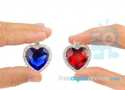 Fingers Holding Blue And Red Jewelry Hearts Stock Photo