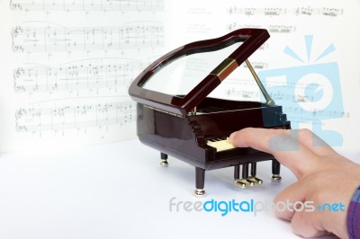 Fingers Playing On Small Model Of Grand Piano Stock Photo