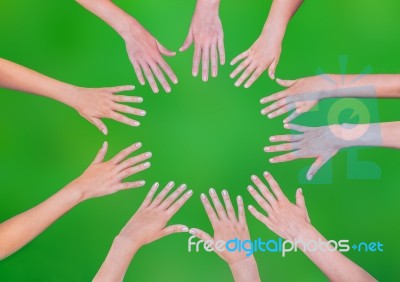 Five Children Hands Joining In Circle Above Green Background Stock Photo