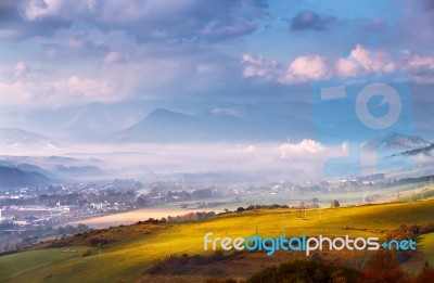 Foggy Sunny Morning In Mountain. Misty Hills. Town In Valley Stock Photo