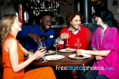 Four Friends Enjoying Dinner At A Restaurant Stock Photo