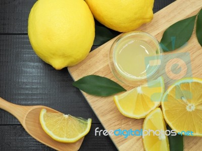 Fresh Lemon Juice In Small Bowl And Lemon Slice On Dark Wood Bac… Stock Photo