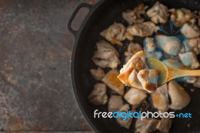 Fried Chicken In The Wooden Spoon With Blurred Pan Stock Photo