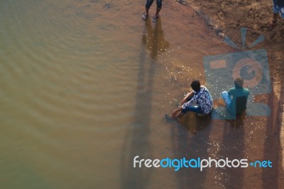 Friends Sitting On Stones Near The Shore Of The Bharatha River Stock Photo