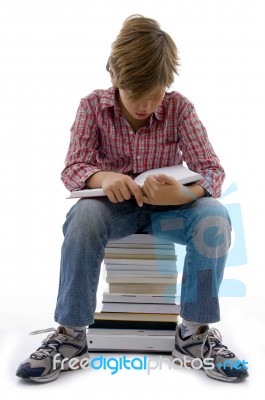 Front View Of Boy Sitting On Books On White Background Stock Photo