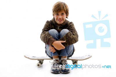 Front View Of Boy Sitting On Skateboard Stock Photo