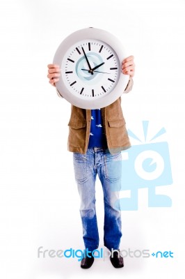 Front View Of Young Man Hiding His Face With Watch Stock Photo