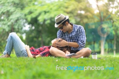 Full Length Of Happy Female Lying On Happy Man Lap In Park Stock Photo