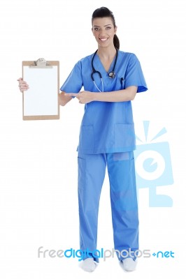 Full Length Of Young Nurse Pointing Blank Clipboard Stock Photo