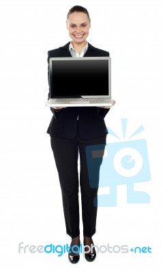 Full Length Portrait Of Woman Presenting New Laptop Stock Photo