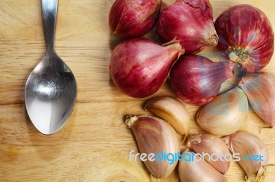 Garlic And Spoon On Chopping Block Stock Photo