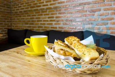 Garlic Bread Served In Basket With Cup Of Coffee On Table Stock Photo