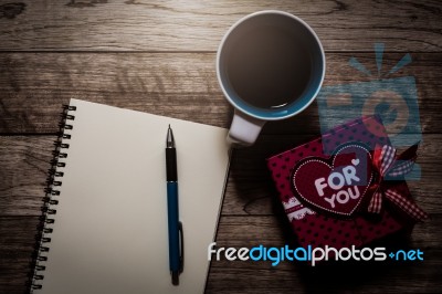 Gift Box, Notebook, Pen And Coffee On Wooden Plank Stock Photo