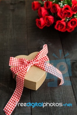 Gift  With A Red  Bow And Bouquet Of Roses Stock Photo