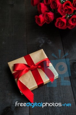 Gift  With A Red  Bow And Bouquet Of Roses Stock Photo