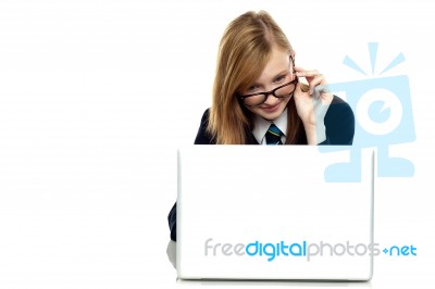 Girl Adjusting Her Spectacles While Working On Laptop Stock Photo