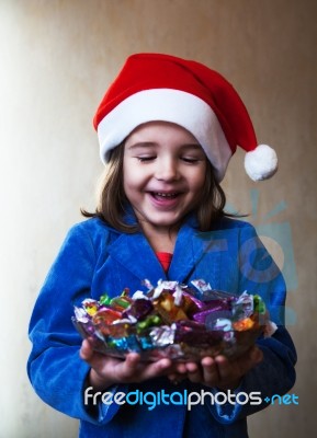 Girl In A Christmas Cap Holds A Dish With Chocolates Stock Photo