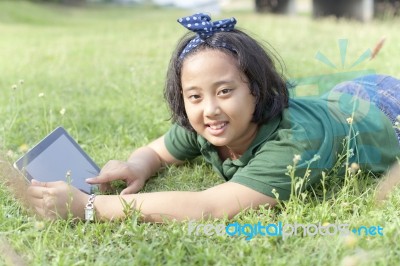 Girl Playing Computer Tablet On Green Field Stock Photo