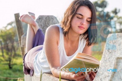 Girl Reading Book Outdoors Stock Photo