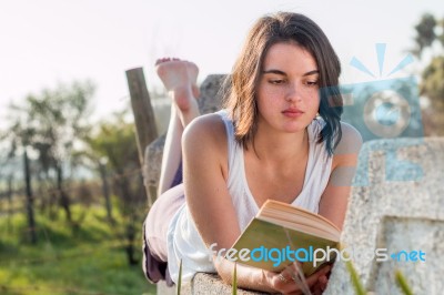 Girl Reading Book Outdoors Stock Photo