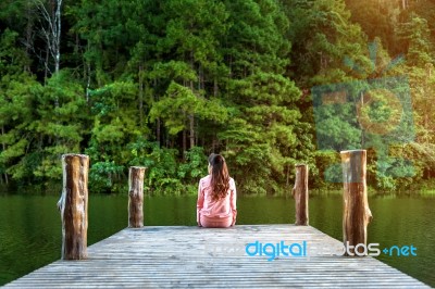 Girl Sitting Alone On A The Wooden Bridge On The Lake. Pang Ung, Thailand Stock Photo