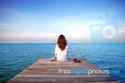 Girl Sitting Alone On A The Wooden Bridge On The Sea. (frustrated Depression) Stock Photo