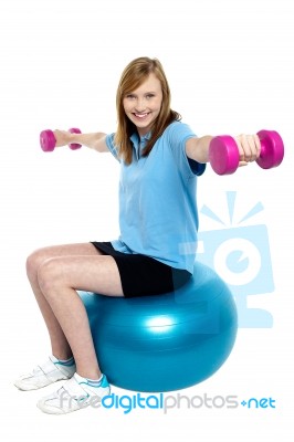 Girl Sitting On Pilates Ball And Doing Dumbbells Stock Photo