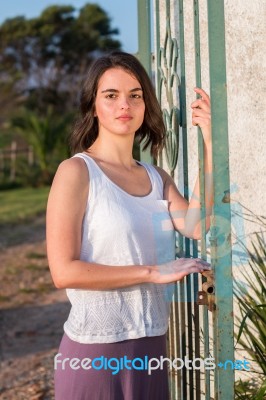 Girl Standing At Gate Outdoors Stock Photo